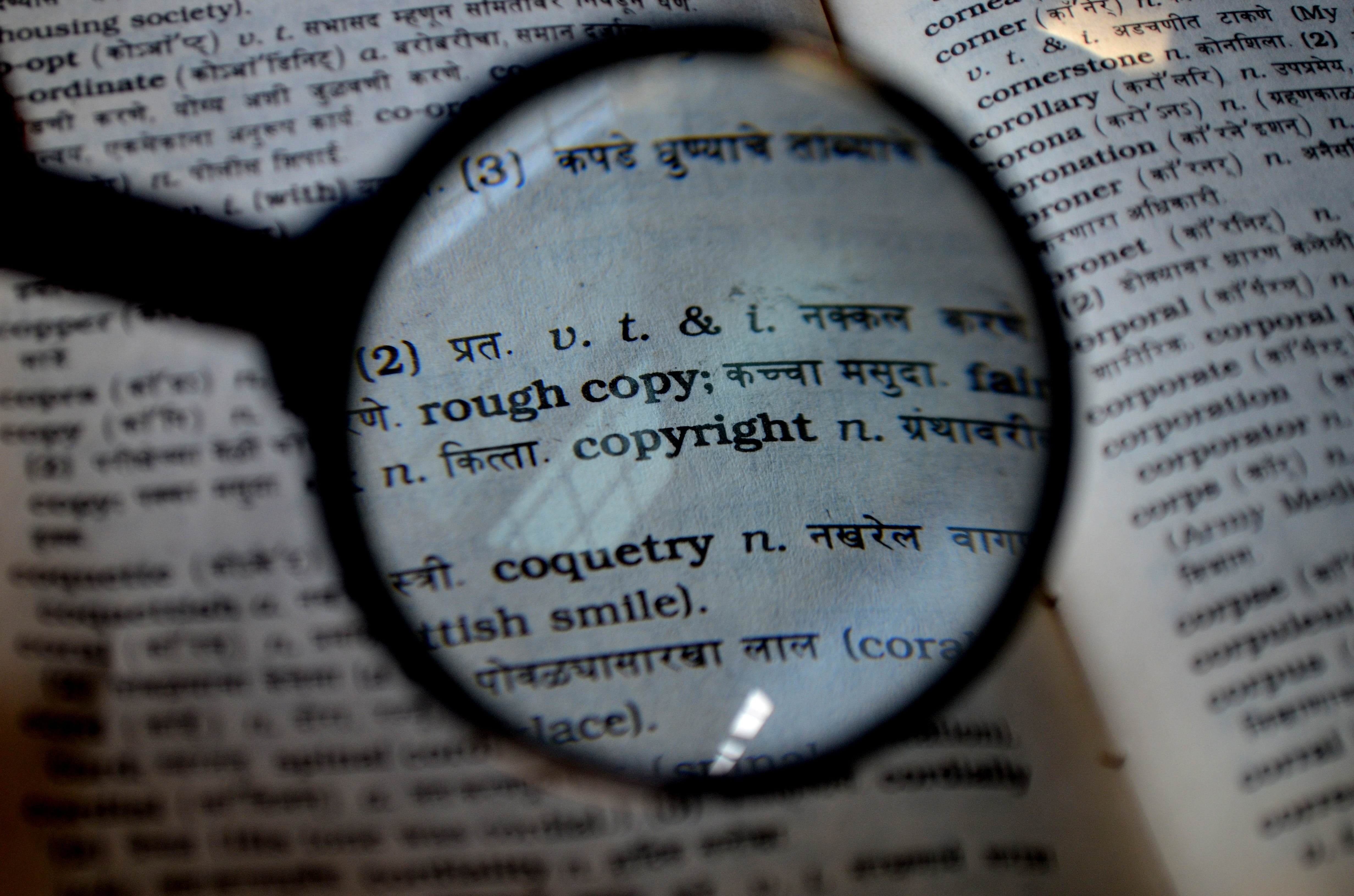Das Bild zeigt eine Lupe über einem Buch und das Wort copyright ist im Fokus.
